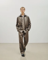 Model Luke Clod in a taupe jacket and trousers against a neutral background for Theory Mens Spring 2026