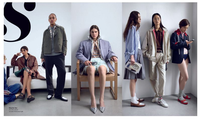 Fashion editorial shot of five women modeling clothing in a studio setting with a white wall backdrop and natural lighting showcasing style.