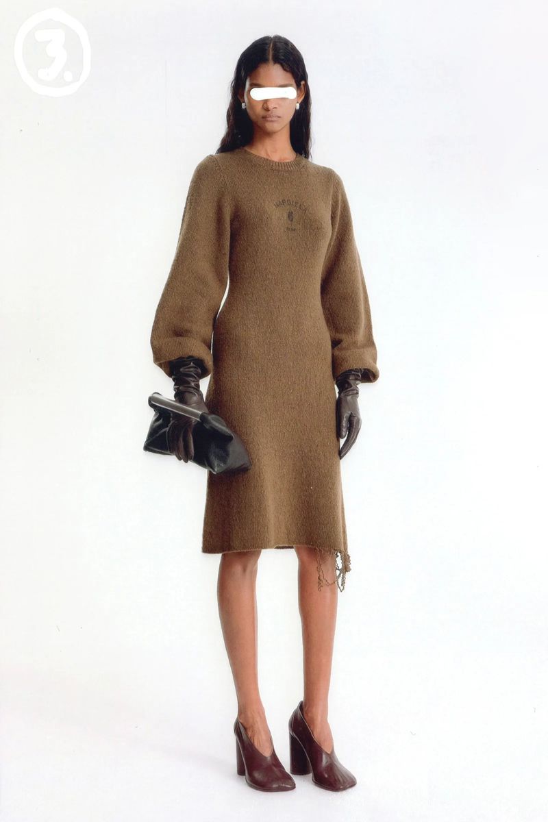 A woman in a brown dress poses in a studio with a black clutch and brown heels, styled in a fashion editorial against a white backdrop.