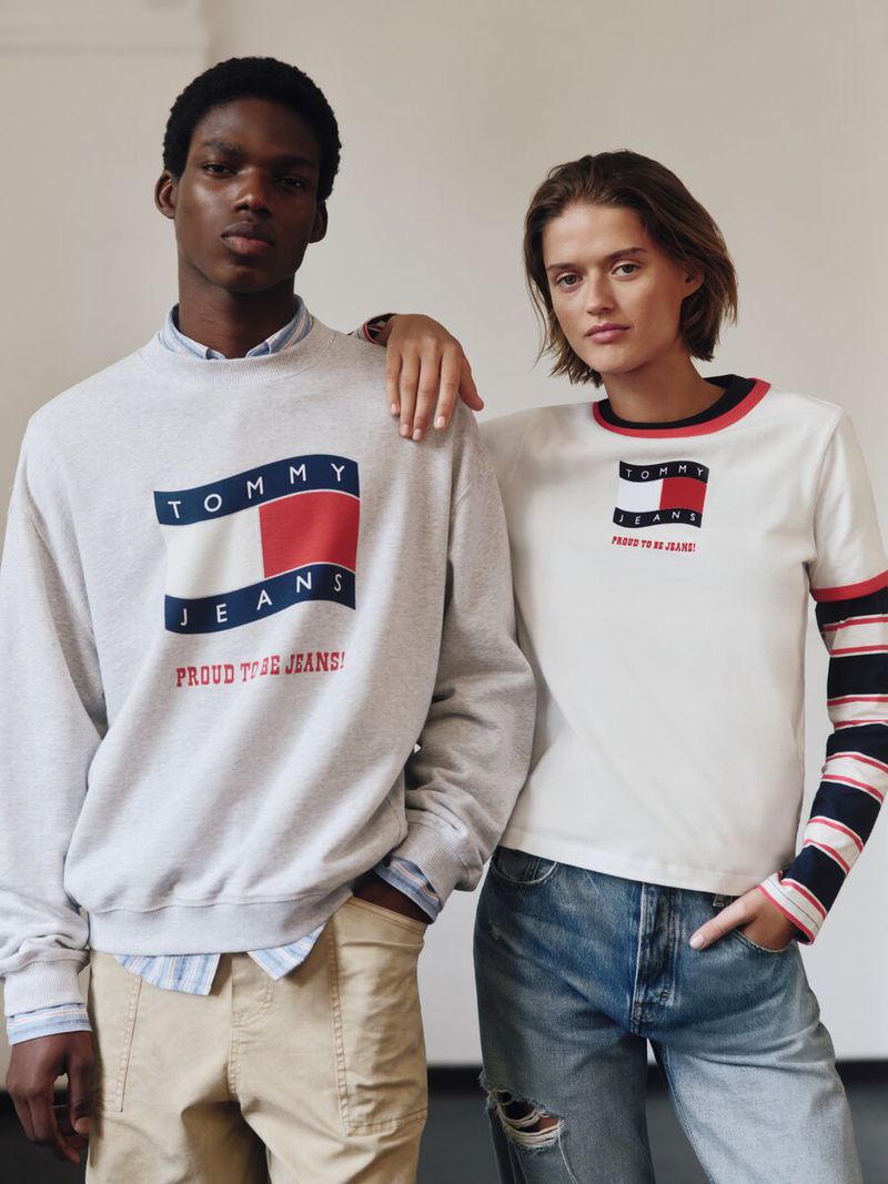 Two models, one adult male and one adult female, are wearing Tommy Jeans branded apparel against a light colored background.