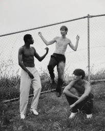Three shirtless male models posing outdoors in front of a chain-link fence for COAT Magazine editorial Boys Like Us.