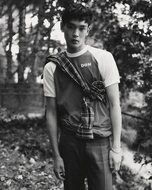 Monochrome portrait of a young man wearing a raglan t-shirt with a plaid shirt tied across his chest.