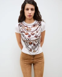 Model wearing a printed white t-shirt and brown trousers against a white background