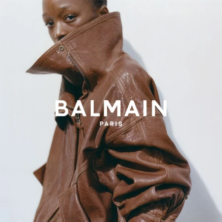 Model wearing an oversized brown leather jacket with a high structured collar against a plain white background.