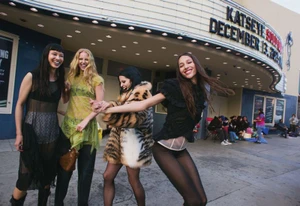 Four female models walking outdoors in front of a cinema marquee for an American Vogue fashion editorial by Cameron McCool