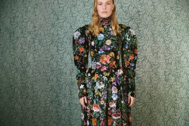 Model Astrid Ostergaard in a black floral embroidered dress standing against patterned green wallpaper for Muse Issue 67.