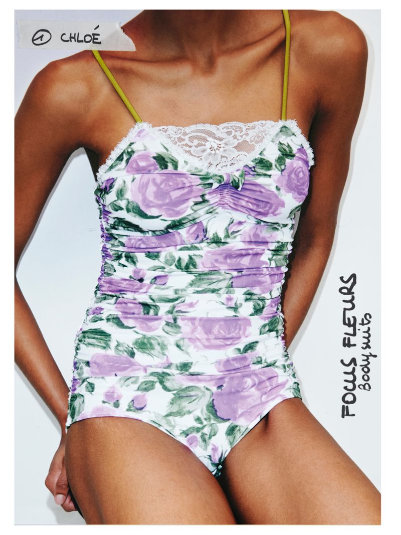 Woman wearing a floral bodysuit with spaghetti straps against a white background. The bodysuit features a lilac rose pattern.