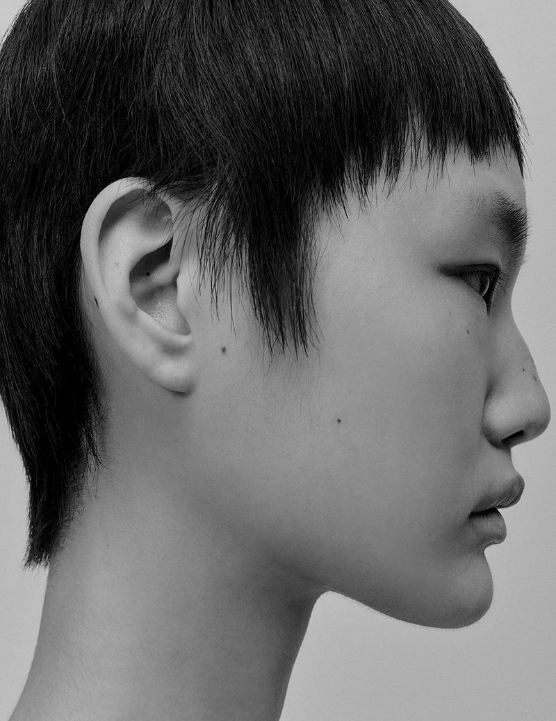 Monochromatic side-profile shot of an Asian woman with short, dark hair against a plain background in a beauty or fashion setting.