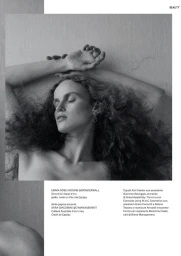 Black and white portrait of model Emma Rose Higgins lying with arms raised and eyes closed against a textured background