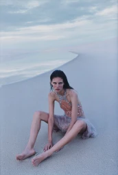 Model Rosalieke Fuchs sitting barefoot on sand dunes under an overcast sky for Harper's Bazaar U.S. Oasis Effect editorial