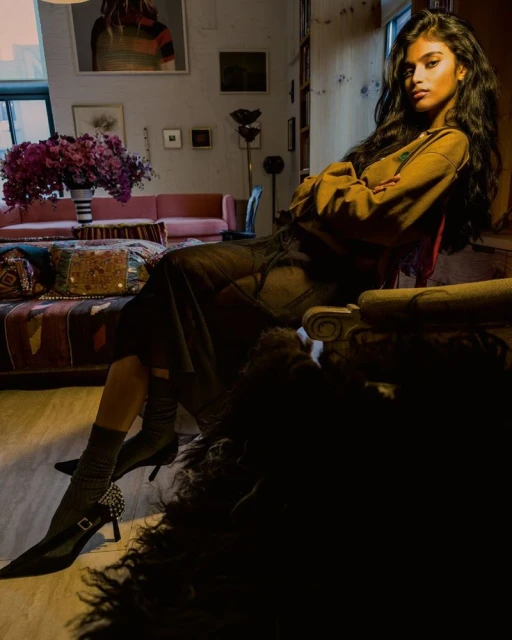 Model Bhavitha Mandava seated indoors wearing a brown top and dark skirt, photographed by Inez and Vinoodh for i-D Magazine.