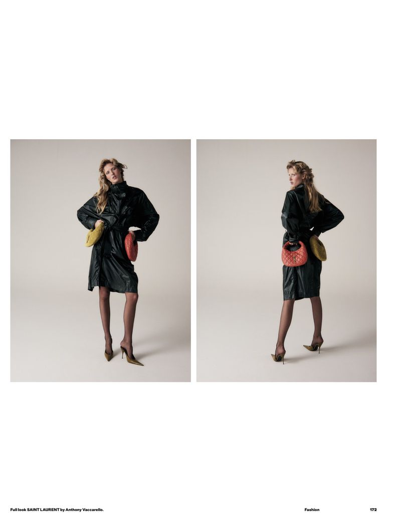Fashion editorial shot of a blonde woman wearing a black dress with colorful round purses, posing in a photo studio with a neutral backdrop.