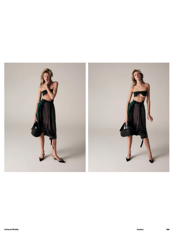 Model wearing a black bandeau top, draped skirt, and heels, holding a handbag against a light seamless studio backdrop