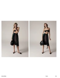 Model wearing a black bandeau top, draped skirt, and heels, holding a handbag against a light seamless studio backdrop
