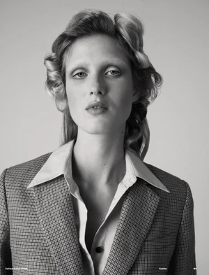 Black and white portrait of a female model wearing a patterned blazer and collared shirt against a grey background