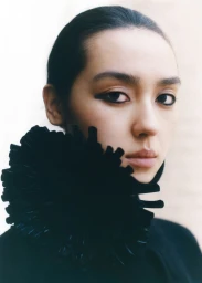 Close-up portrait of a woman wearing a black ruffled collar for T Magazine China photographed by Hailun Ma.