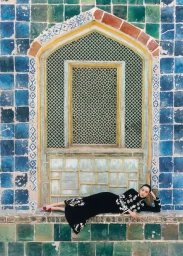 Woman in black embroidered dress lying on a tiled ledge beneath an ornate window for T Magazine China