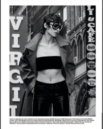 Model wearing dark oversized sunglasses, bandeau top, and trench coat posing on a city street in a black and white editorial photograph.
