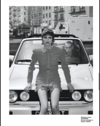 Model leaning on the front of a white convertible car in an urban street setting for a Numéro France fashion editorial
