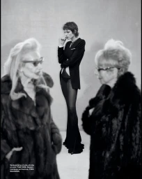 Black and white fashion editorial featuring three women, with two older women in fur coats blurred in the foreground and a sharp model standing behind