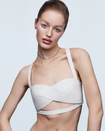 Model wearing a white strapless crop top and rhinestone choker against a plain light grey studio background.