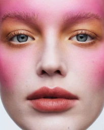 Close-up beauty portrait of a woman with vibrant pink and orange eye makeup against a clean white backdrop.