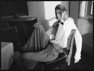 Model with long hair seated on a chair wearing a white blouse and trousers for Harper's Bazaar Italia by Zoë Ghertner
