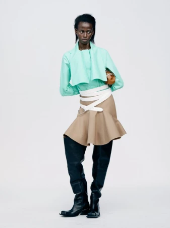 Model in mint green top, beige skirt with white multi-wrap belt, and black boots against a white studio background.