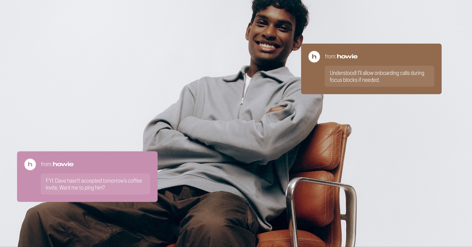 Person seated in chair with chat bubbles. Man in grey shirt and brown pants smiles in front of a white backdrop with text bubbles.