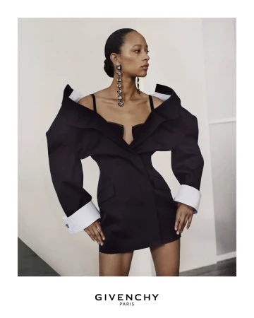 Elegant woman wearing oversized black blazer dress and statement earrings in a studio setting. Fashion and beauty shot.