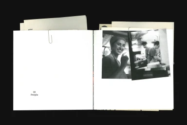 Open book page showing black and white photographic prints attached with paper clips and typography reading III People