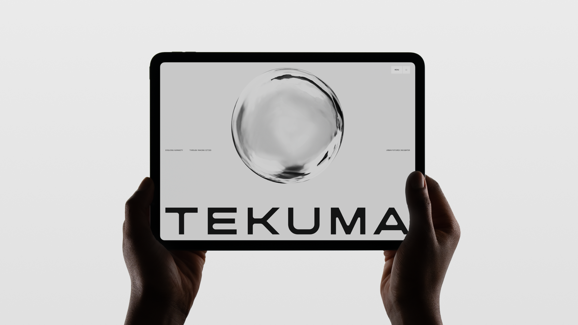 Hands hold a black tablet displaying a website with a grayscale abstract sphere and the name TEKUMA in bold letters on a light gray screen.