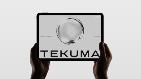 Two hands holding a tablet displaying the Tekuma brand identity with a central liquid sphere graphic.
