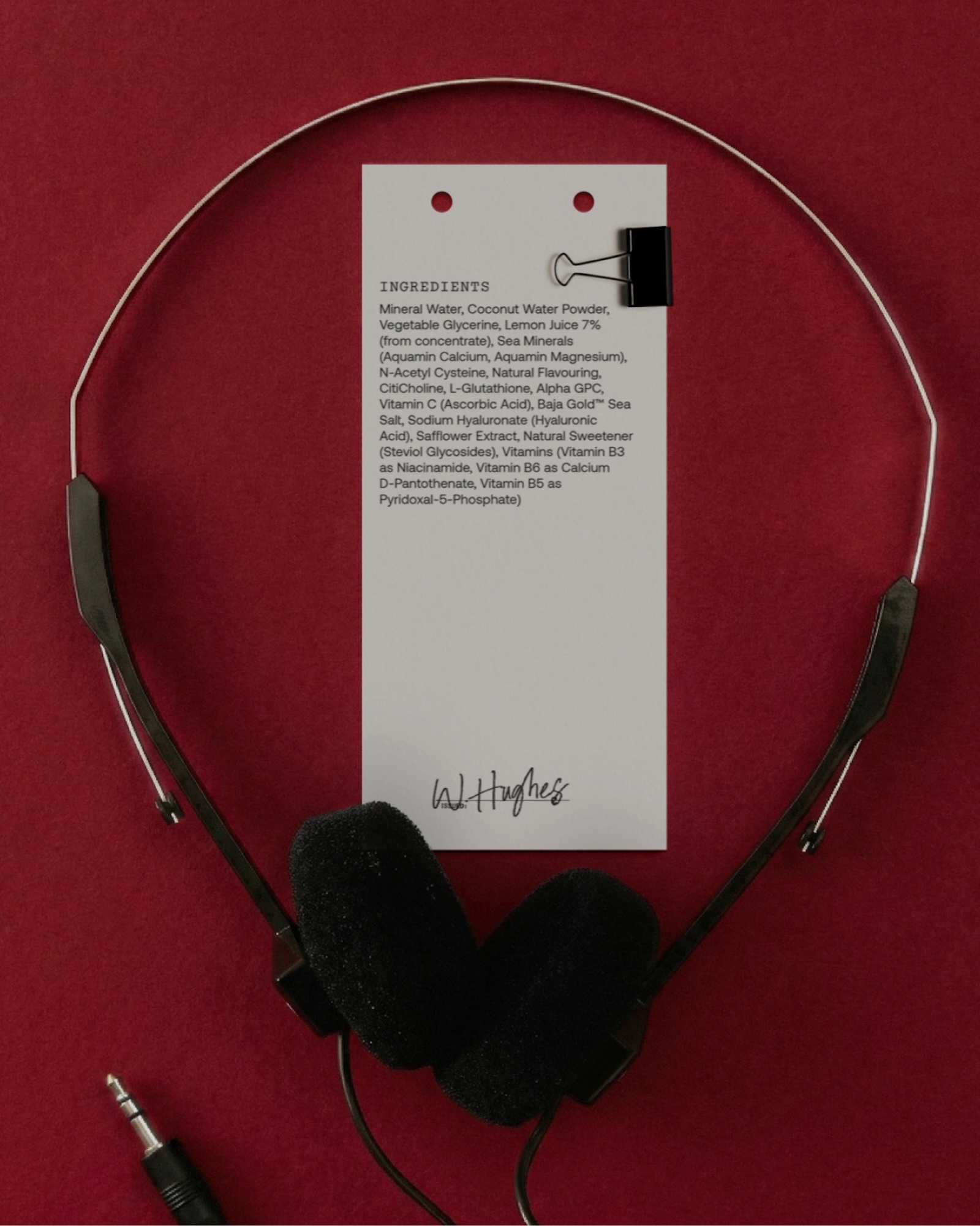 Overhead shot of black headphones against a red backdrop, accompanied by a white card detailing the product ingredients.