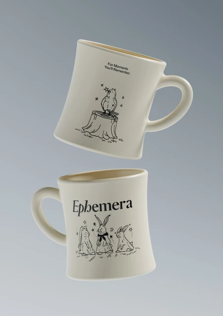 Two white ceramic coffee mugs with illustrated designs of an owl and rabbits float on a gray background in a product shot.