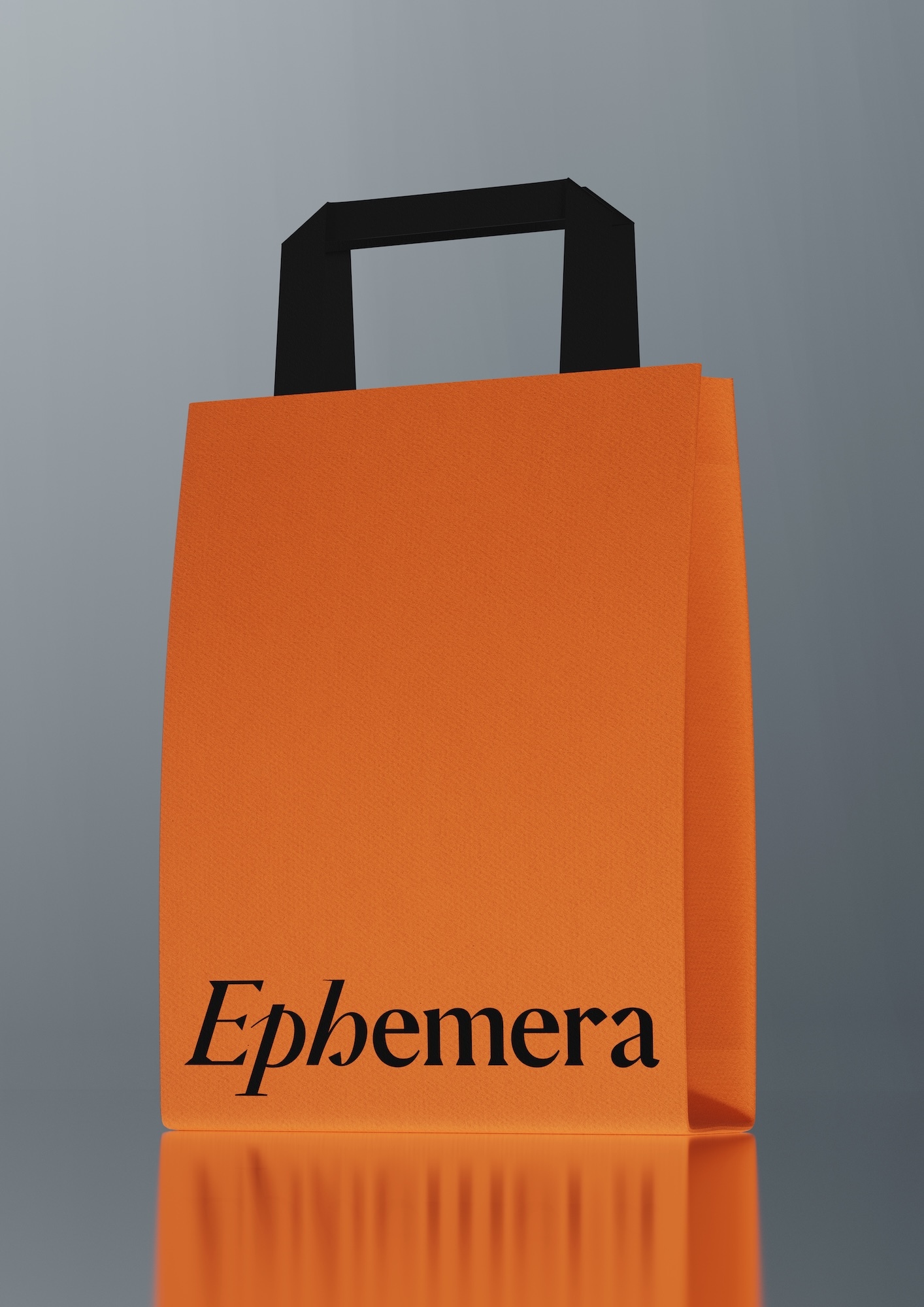 Studio shot of an orange paper shopping bag with a black handle, displaying the word 'Ephemera' in black text on the front.