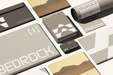 High-angle flat lay view of corporate identity collateral for Bedrock Robotics including branded notebooks, cards, and packaging tubes on a white surface.