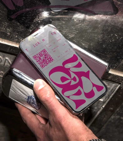Man holding smartphone with a ticket QR code on the screen, ready for scanning or entry, photographed in a close up shot.