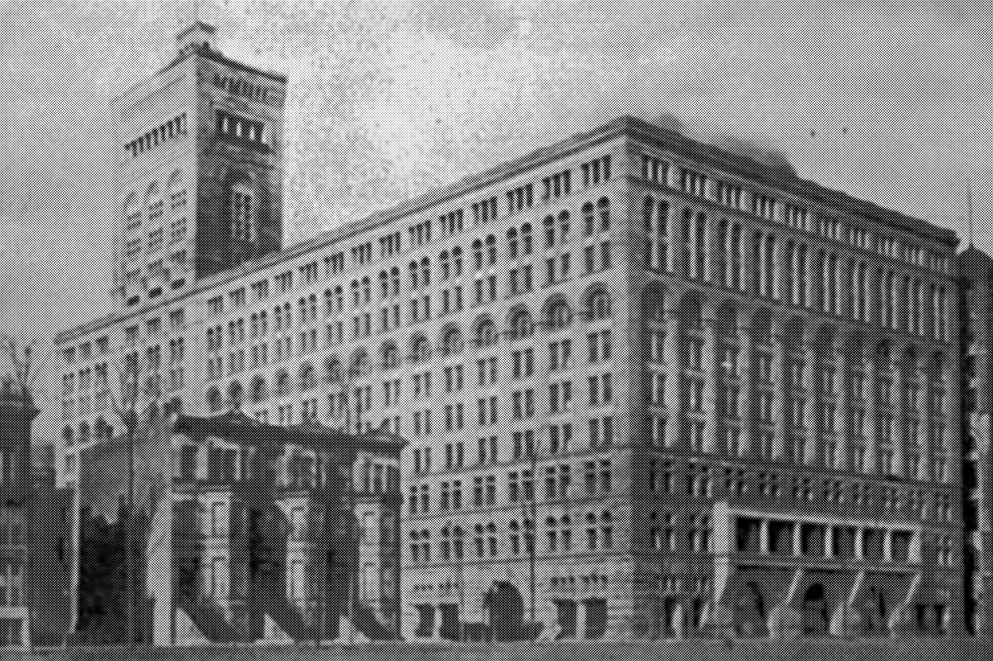 Large historic building with a tower, showcasing architectural details in a monochrome image, emphasizing structure and design.