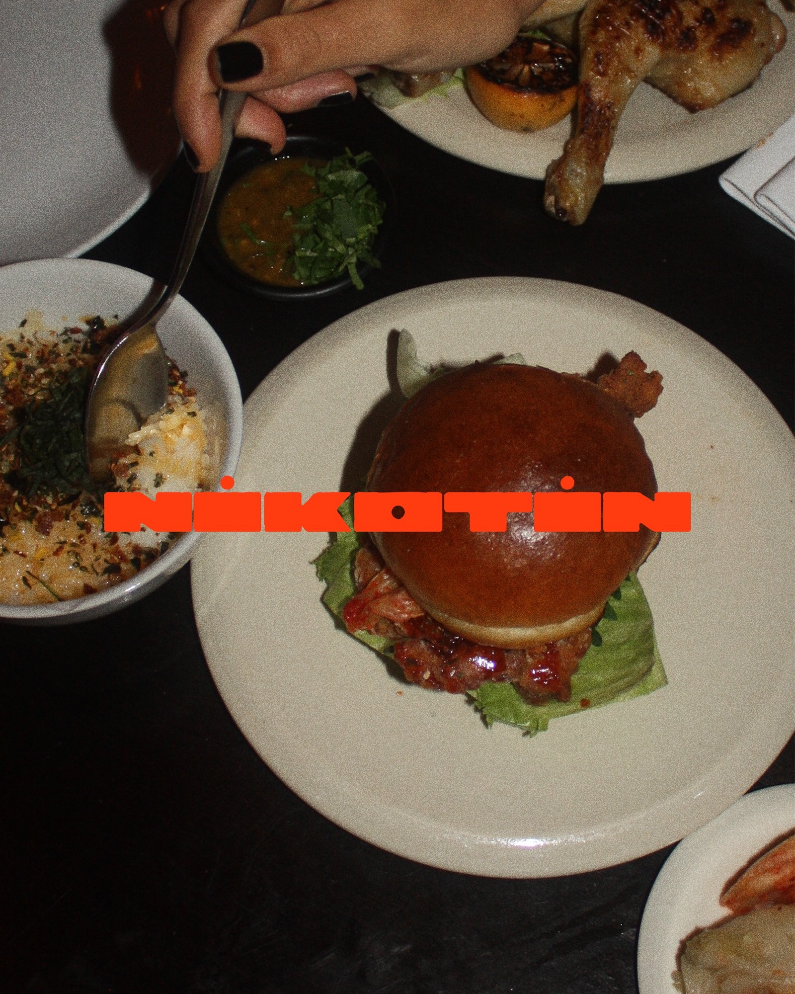 Overhead shot of a burger, chicken leg, and side dishes on a table, showcasing a meal setting with plates and food arrangements.