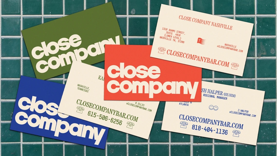 Collection of colorful business cards displaying 'Close Company' branding on a green tile background in a flat lay composition.