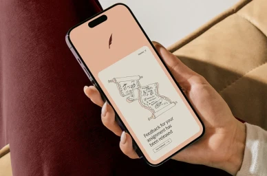Close-up of a person holding a modern smartphone displaying a warm UI screen with a scroll illustration for Cadmus.