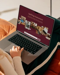 Person using a modern laptop displaying a digital brand identity website on screen while seated on a couch.
