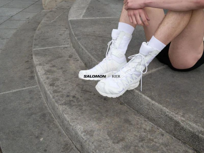 Person wearing white high-top sneakers and white socks sitting on curved stone steps outdoors