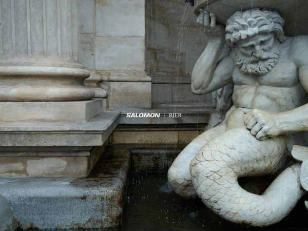 Close-up of a carved marble fountain sculpture featuring a bearded male figure beside classical architectural columns.