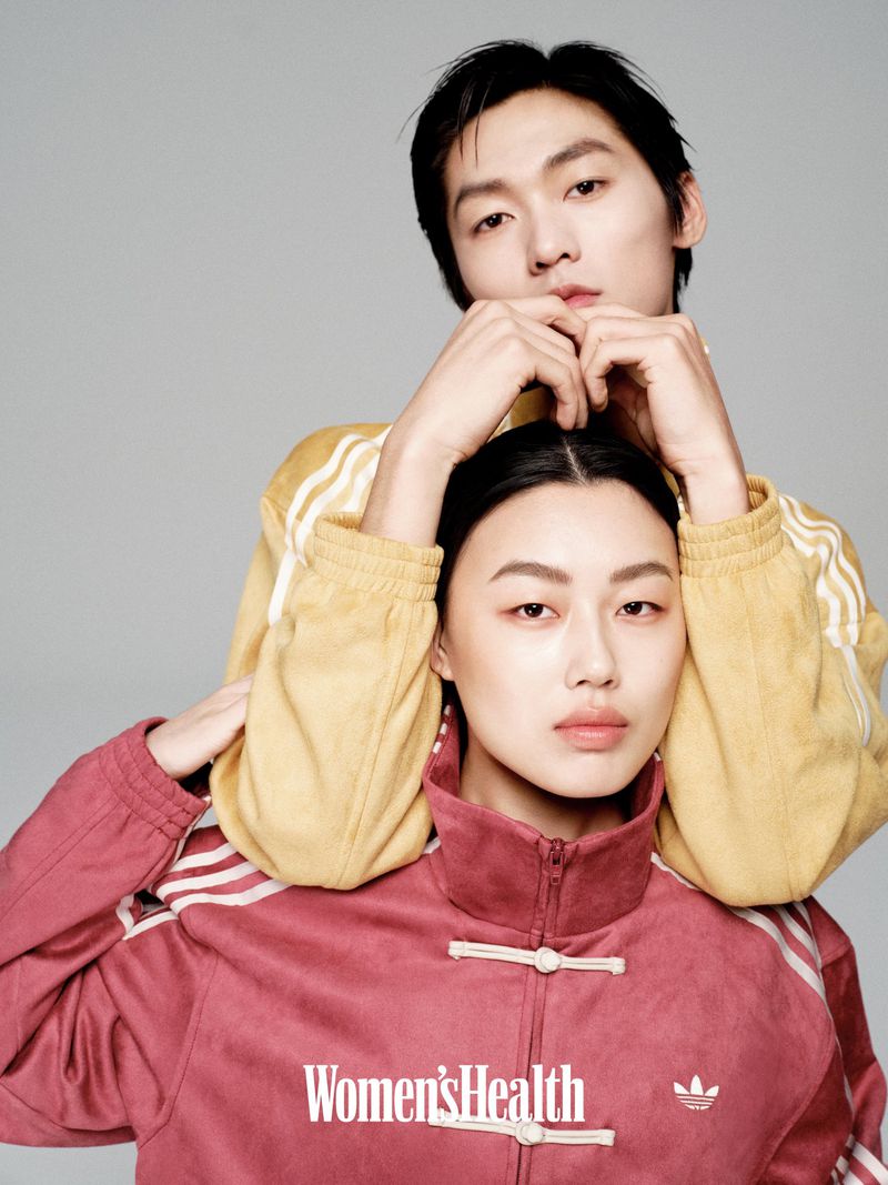 Two Asian adults pose indoors against a grey background; the female model wears a pink jacket, and the male model wears a yellow jacket.