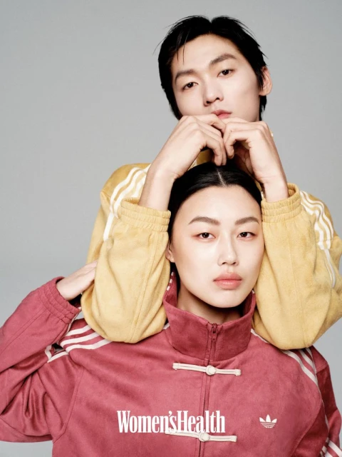 Two Asian adults pose indoors against a grey background; the female model wears a pink jacket, and the male model wears a yellow jacket.