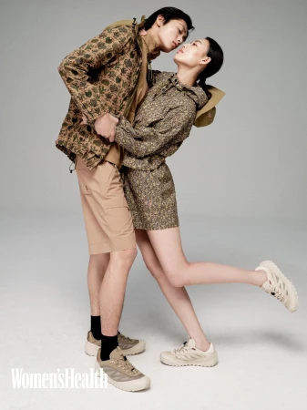 Two models in matching floral patterned outdoor jackets leaning into a romantic pose against a plain light grey backdrop