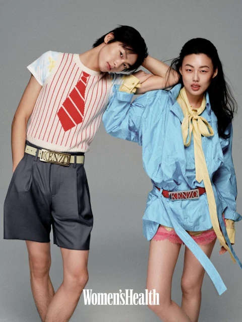 Two Asian fashion models strike a pose in a studio, the man wearing a white shirt with red tie, the woman a blue top and matching belt.