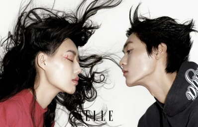 Close-up profile shot of a woman with red shirt and man in dark hoodie facing each other against a white background